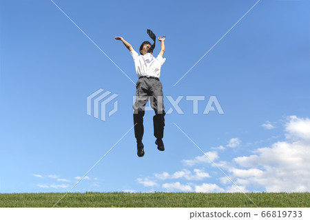 Male high school student jumping while happily against the blue sky Male high school student jumping while happily against the blue sky 66819733