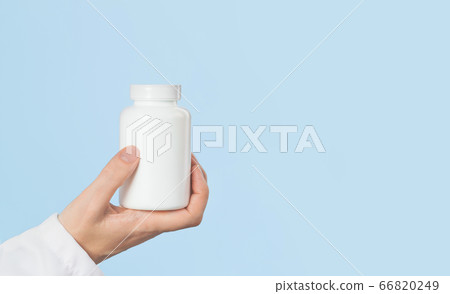 Hand of female doctor holds white pills jar Hand of female doctor holds white pills jar 66820249