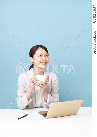 A woman having a tea while working at a computer A woman having a tea while working at a computer 66825634