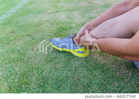 Male athlete applying compression bandage onto ankle injury of a football player, Sports injuries. 66827348