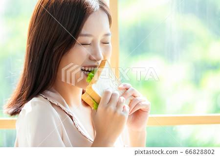Woman in pajamas having breakfast 66828802