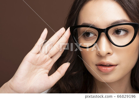 一個年輕的女人,戴著眼鏡的面部表情 一個年輕的女人,戴著眼鏡的面部表情 66829196