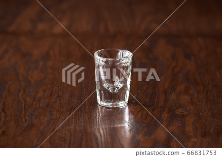 Empty elegant shot glass on the dark wooden table Empty elegant shot glass on the dark wooden table 66831753