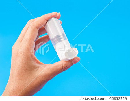 Person holding a white asthma inhaler. 66832729