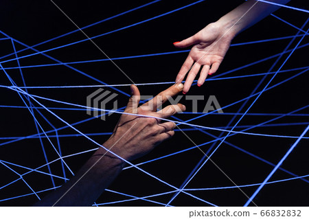 Image of male and female hand among threads in ultraviolet 66832832