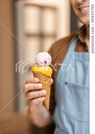 Seller with ice cream in a waffle cone, close-up 66833760