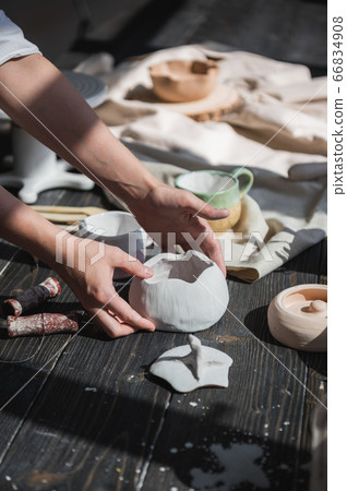 Female potter making ceramic dishes at her studio. Working process of glazing ceramic bowl. 66834908