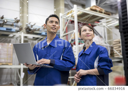 Men and women who manage products while looking at laptops in a distribution warehouse 66834916