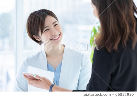 一個年輕的女人,一邊看著商務智能手機交談 一個年輕的女人,一邊看著商務智能手機交談 66835950