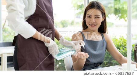 Waitress push hand sanitizer for customer. Waitress push hand sanitizer for customer. 66837627