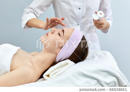 beautician applies the mask to the face of woman beautician applies the mask to the face of woman 66838661