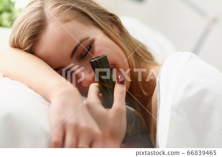 Cheerful young woman with wine waking up after night party 66839465