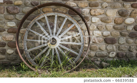 Antique cartwheel and iron rim near the stone wall of the tavern Antique cartwheel and iron rim near the stone wall of the tavern 66839588