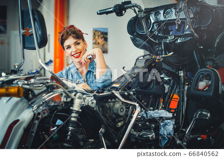 beautiful girl posing repairs a motorcycle in a beautiful girl posing repairs a motorcycle in a 66840562