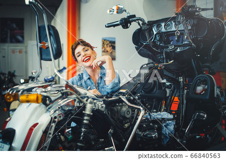 beautiful girl posing repairs a motorcycle in a beautiful girl posing repairs a motorcycle in a 66840563