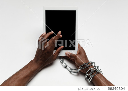 Close up of human hand using tablet with blank black screen. Tied with chain, addiction Close up of human hand using tablet with blank black screen. Tied with chain, addiction 66840804