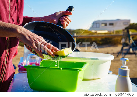 Woman washing dishes in bowl, capming outdoor Woman washing dishes in bowl, capming outdoor 66844460