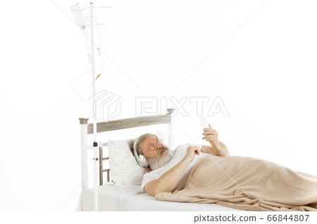 Elderly old man recovering in a hospital bed isolated on white 66844807