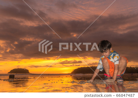 A cute boy playing sand on the beach 66847487