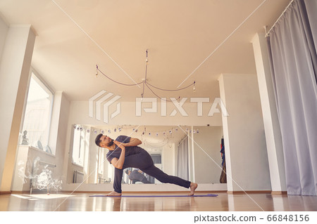 Male yoga practitioner doing prayer twist pose 66848156