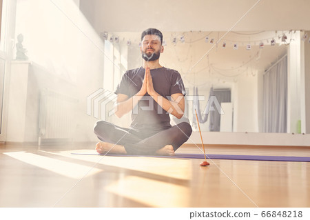 Handsome young man meditating in yoga studio Handsome young man meditating in yoga studio 66848218