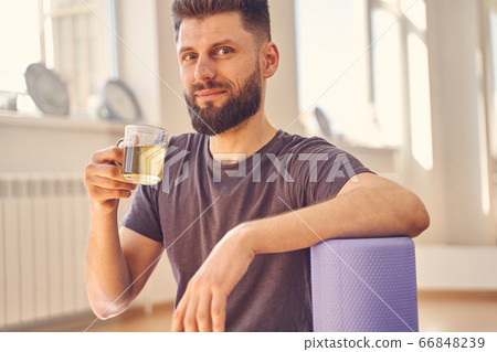 Bearded young man drinking herbal tea in yoga studio 66848239
