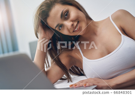 Cheerful young woman using notebook at home Cheerful young woman using notebook at home 66848301
