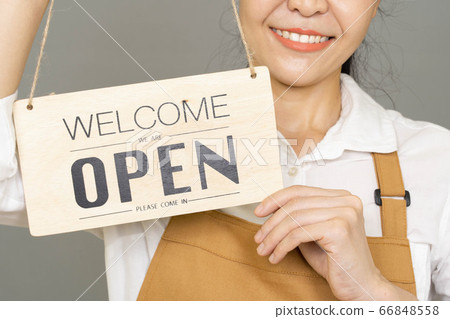 Selective focus Small business owner woman smiling and holding the sign for the reopening of the place after the quarantine Selective focus Small business owner woman smiling and holding the sign for the reopening of the place after the quarantine 66848558