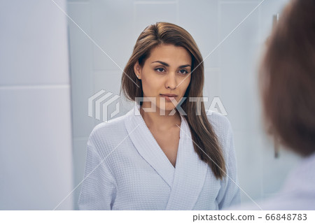 Attractive young woman looking in the mirror Attractive young woman looking in the mirror 66848783