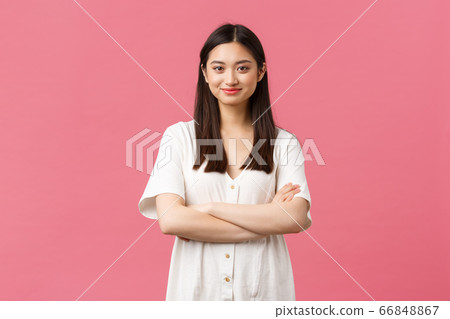 Beauty, people emotions and summer lifestyle concept. Tender young asian girl in cute dress smiling camera, standing with crossed hands and professional determined look, pink background 66848867