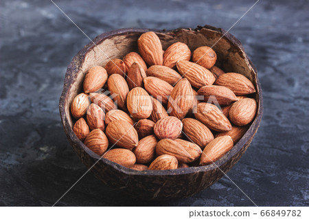 Almonds in coconut shells on a dark background Almonds in coconut shells on a dark background 66849782
