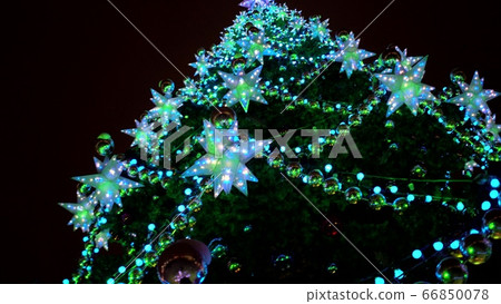Close up large luminous multi-pointed blue stars and yellow balls decoration on Christmas tree at Christmas market square Close up large luminous multi-pointed blue stars and yellow balls decoration on Christmas tree at Christmas market square 66850078