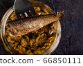 Sprat on a fork over a glass jar 66850111