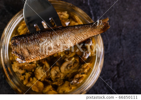 Sprat on a fork over a glass jar 66850111