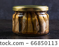 Glass jar of sprats against a dark background 66850113