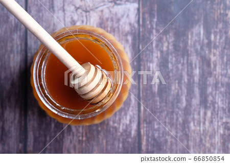 Top view of fresh honey in a jar on wooden table. Top view of fresh honey in a jar on wooden table. 66850854