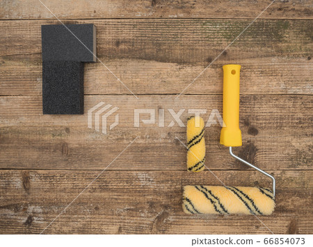 Sponge for sanding and paint roller on a wooden background. Sponge for sanding and paint roller on a wooden background. 66854073