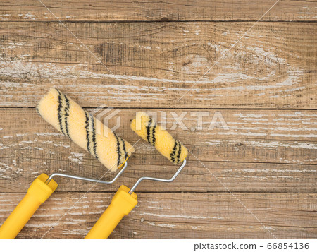 Paint rollers of different sizes on wooden background. 66854136