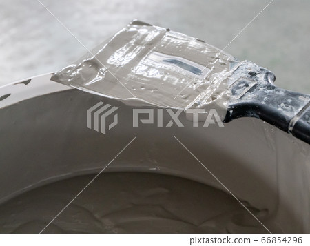 Putty knife and putty in a bucket. Putty knife and putty in a bucket. 66854296