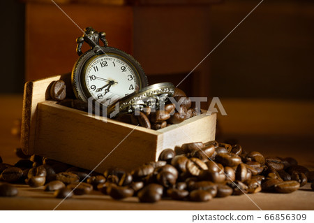 Coffee bean and pocket watch in manual grinder on table. Closeup and copy space. Concept of coffee time in morning. 66856309