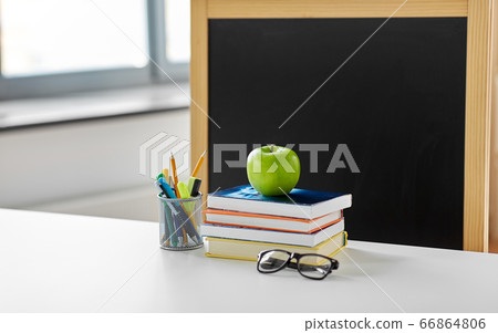 books, apple and school supplies on table at home 66864806