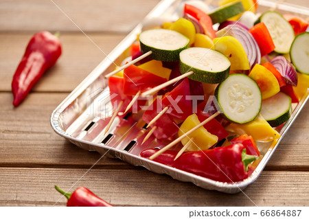 close up of vegetables on skewers on foil grill 66864887
