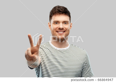 young man showing peace over grey background 66864947