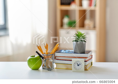 books, magnifier, pencils, apple on table at home 66865004