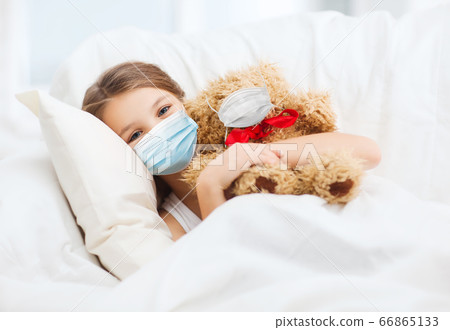 girl wearing medical mask with teddy bear in bed girl wearing medical mask with teddy bear in bed 66865133
