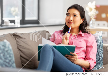 asian woman with diary sitting on sofa at home asian woman with diary sitting on sofa at home 66865436