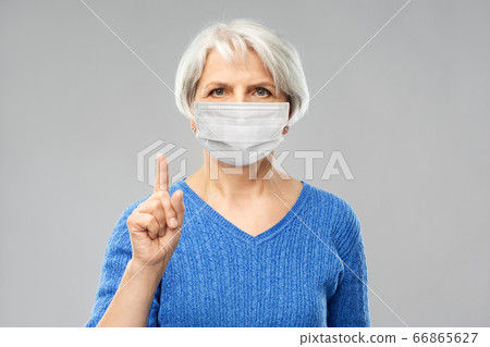 senior woman in medical mask pointing finger up senior woman in medical mask pointing finger up 66865627