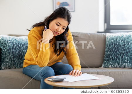 sad asian woman with papers and calculator at home sad asian woman with papers and calculator at home 66865850