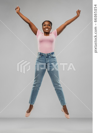 happy african american woman jumping over grey 66865854