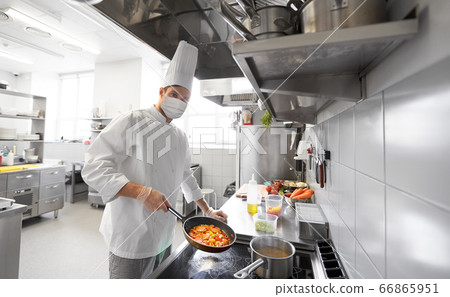 chef in mask cooking food at restaurant kitchen chef in mask cooking food at restaurant kitchen 66865951